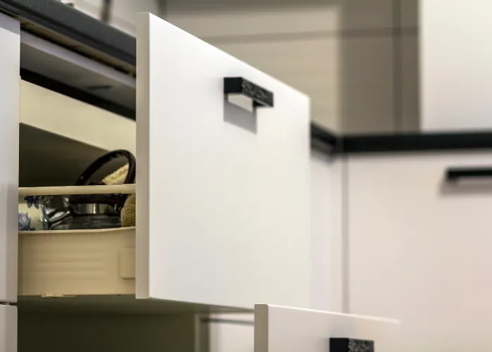 Open kitchen cabinet drawer, with a close-up of the hardware