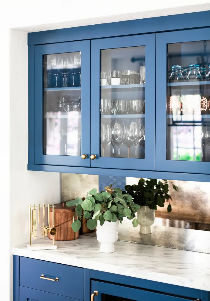 Beautiful Blue kitchen cabinets with glass insets and a white marble countertop