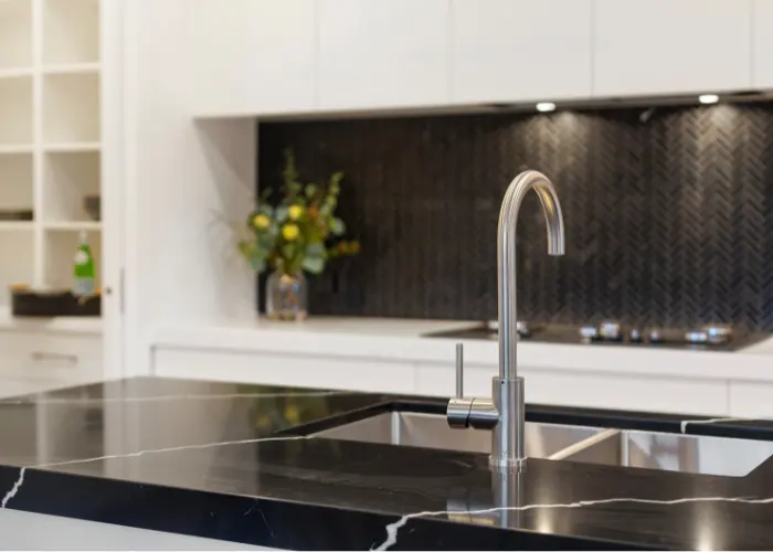 A black marble kitchen countertop with a white vein running through it. In front of a modern fireplace