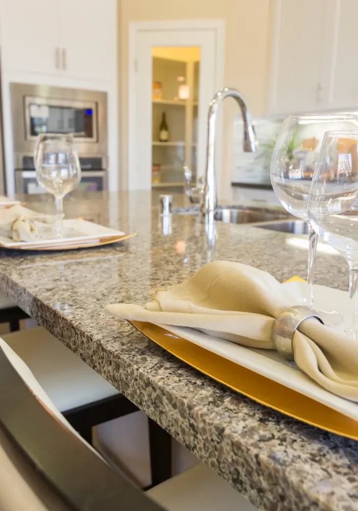 A beautiful earth tone granite kitchen countertop with fancy place settings on it