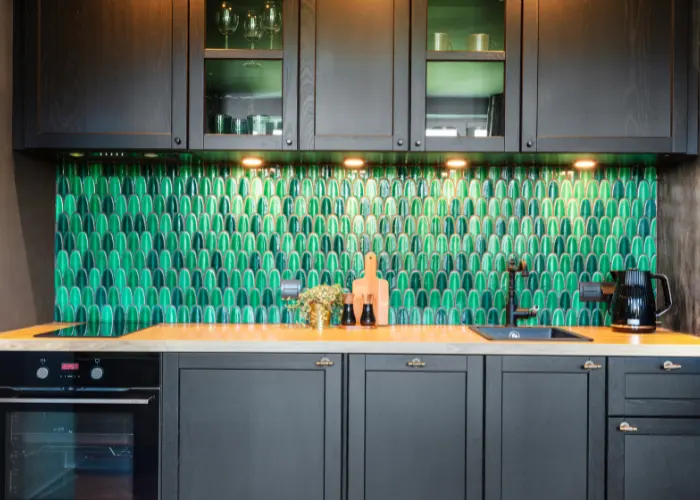 Remodeled kitchen with dark wood cabinet and a beautiful kitchen backsplash with green and black tiles